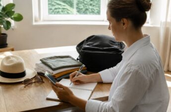 Checklist op tafel met notitieboek en smartphone voor het regelen van een vakantie