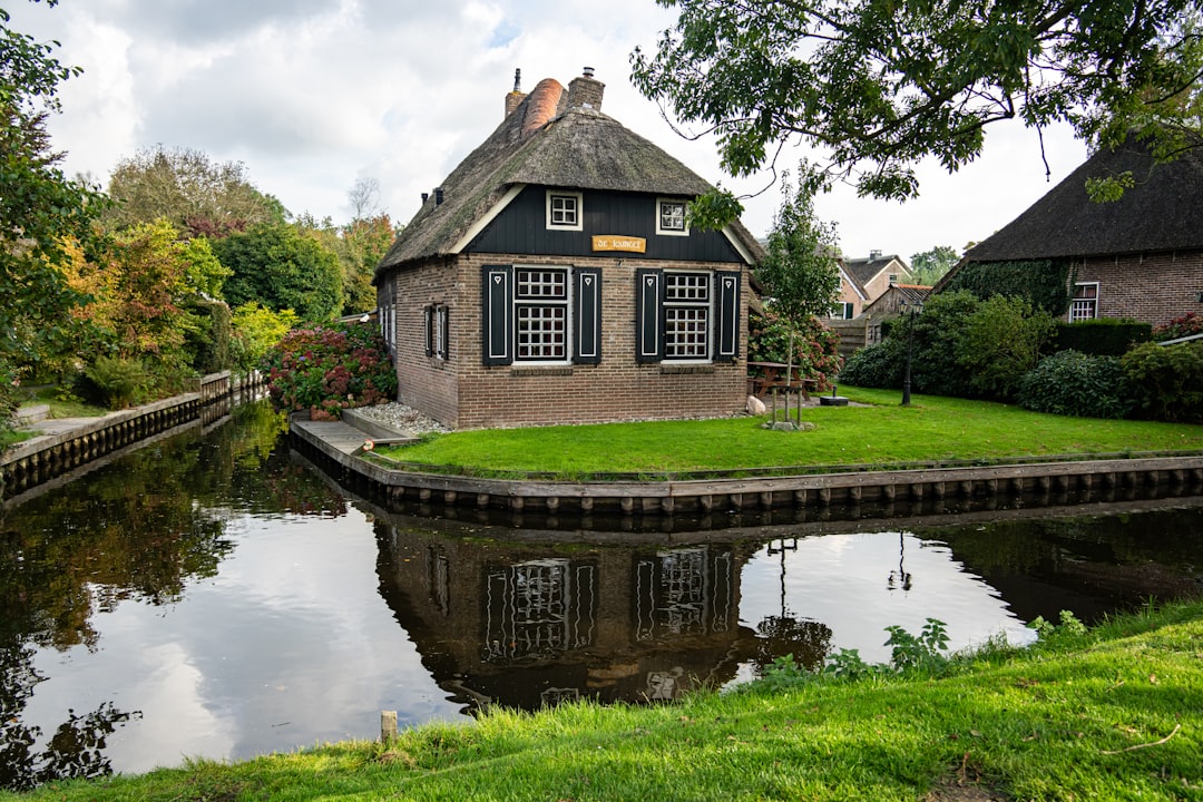 Thatched roof house by a canal with reflection