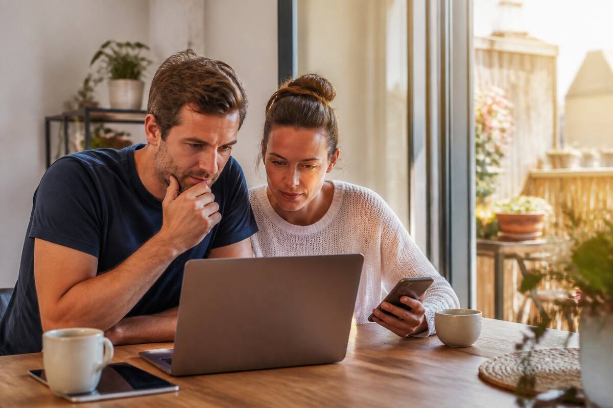 Vakanties vergelijken met laptop en smartphone aan de keukentafel