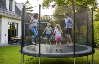 Kinderen springen op een trampoline met veiligheidsnet en randkussen in een tuin